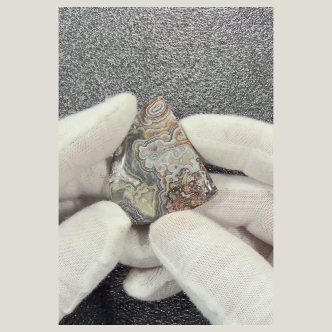 Rotating video of a natural Crazy Lace Agate cabochon showcasing its intricate lace-like banding, earthy colors, and polished finish.