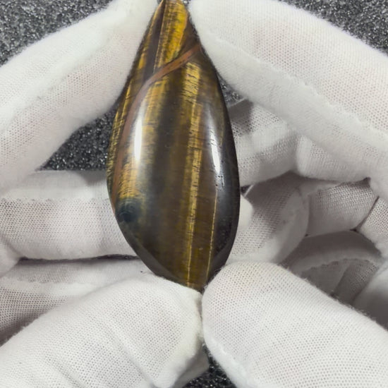 Video showcasing the natural Tiger's Eye cabochon from multiple angles, highlighting its golden chatoyancy, polished finish, and unique natural patterns.