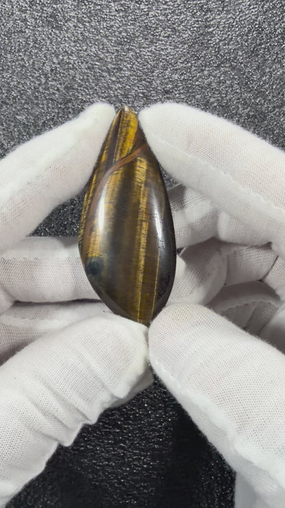 Video showcasing the natural Tiger's Eye cabochon from multiple angles, highlighting its golden chatoyancy, polished finish, and unique natural patterns.