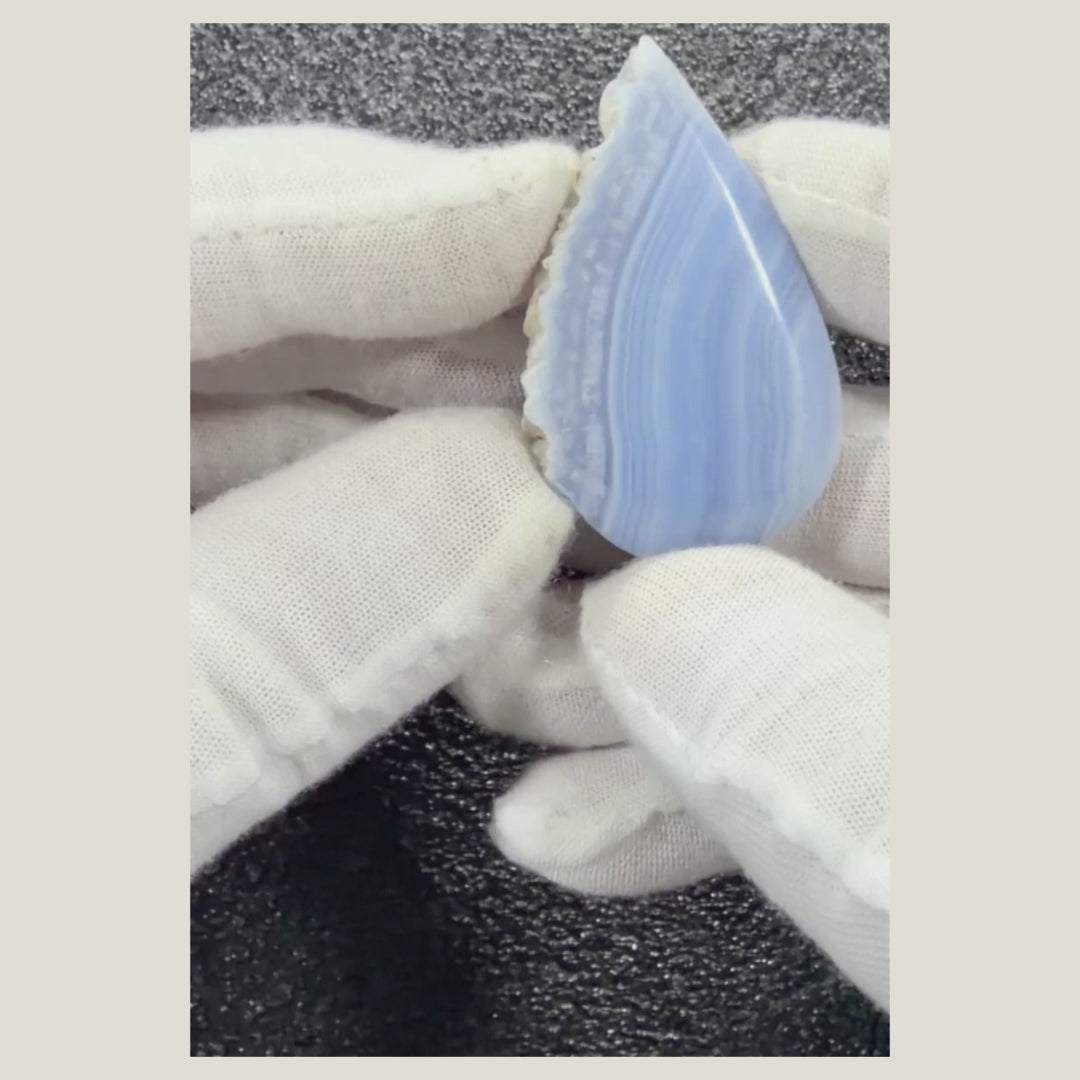 Close-up video of a premium African Blue Lace Agate cabochon featuring glossy polish, flowing blue bands, and natural white veining.