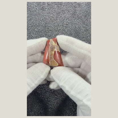 Close-up video of a polished Brecciated Jasper cabochon displaying distinctive natural color variations and intricate stone patterns.