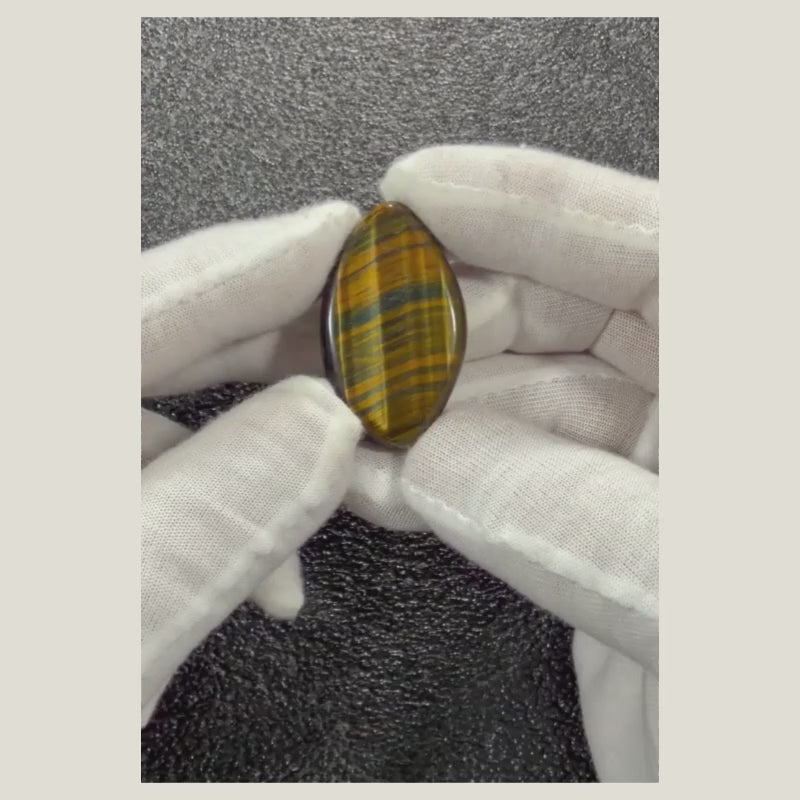 Video showcasing the natural Tiger's Eye cabochon from multiple angles, highlighting its golden chatoyancy, polished finish, and unique natural patterns.