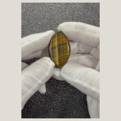 Video showcasing the natural Tiger's Eye cabochon from multiple angles, highlighting its golden chatoyancy, polished finish, and unique natural patterns.