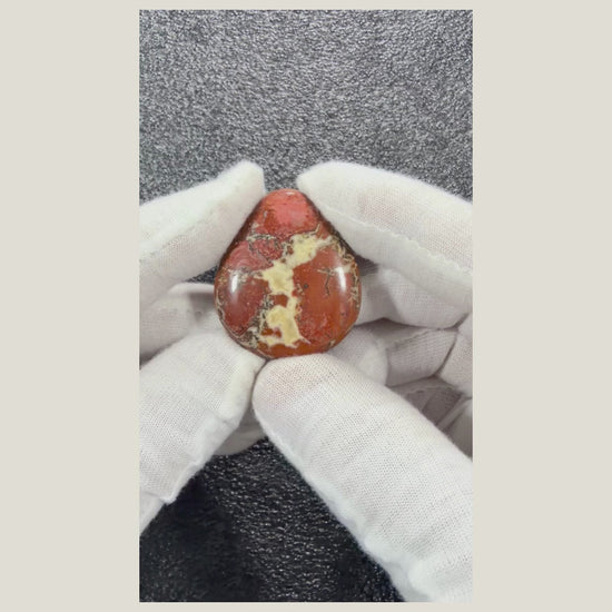 Rotating video of a natural Brecciated Jasper cabochon highlighting its polished finish and rich red, brown, gray, and cream natural patterns.